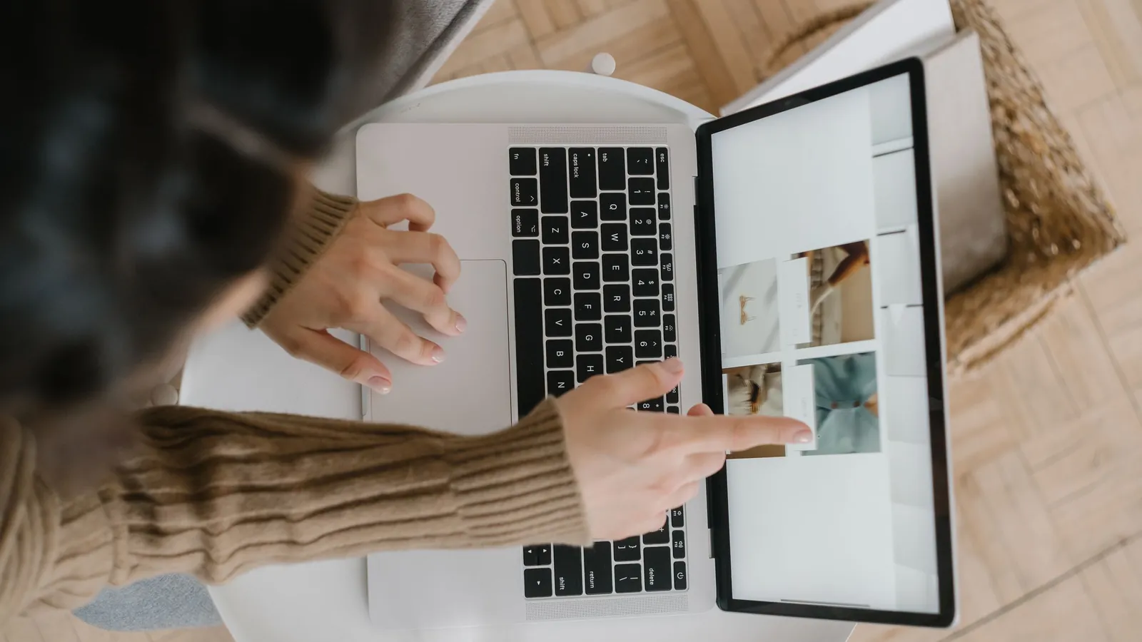 A person pointing at a web page on a laptop screen.